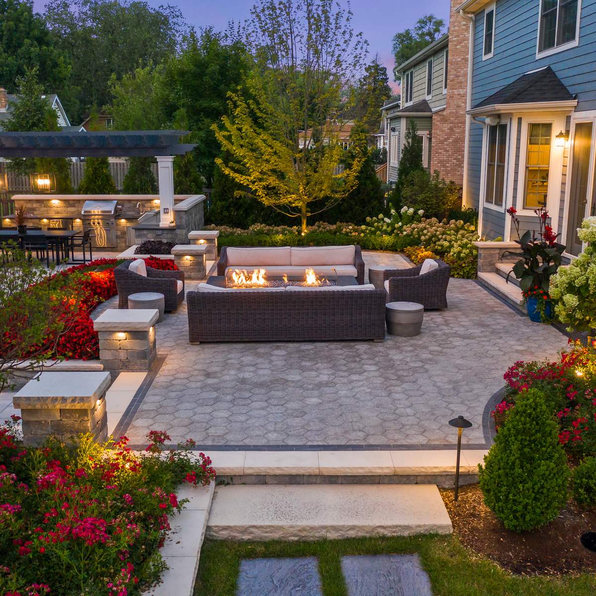 A backyard with a fire pit and seating area made of concrete pavers.