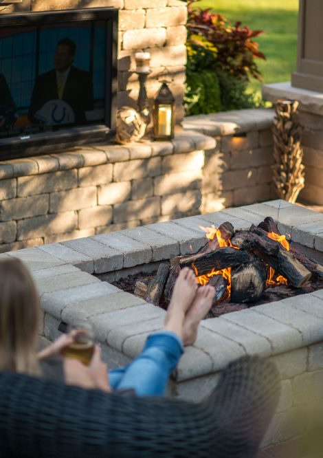 Person lounging by Outdoor Fire Pit and Retaining Wall with TV