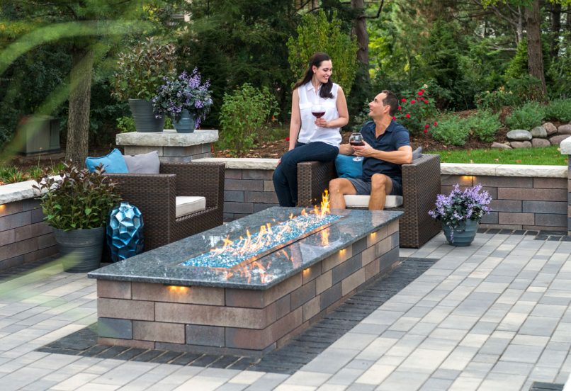 People Enjoying a Drink by Outdoor Fire Feature with Surrounding Retaining Wall