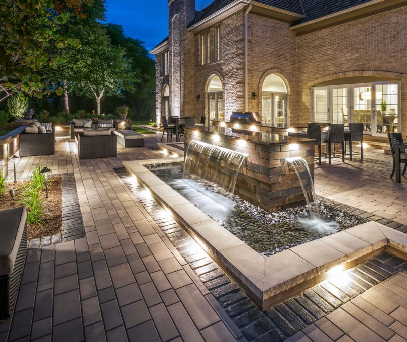 Unilock Outdoor Patio with Waterfall Feature with Retaining Walls and Night Lighting