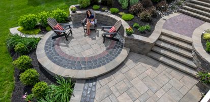 Person Sitting on Circular Patio Design with Retaining Wall and Steps