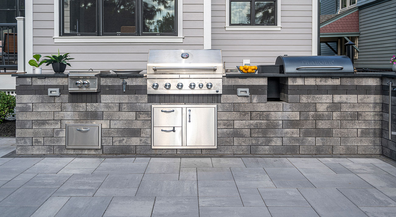 Unilock Lineo Dimensional Stone outdoor kitchen surrounded by Beacon Hill Smooth EnduraColor pavers