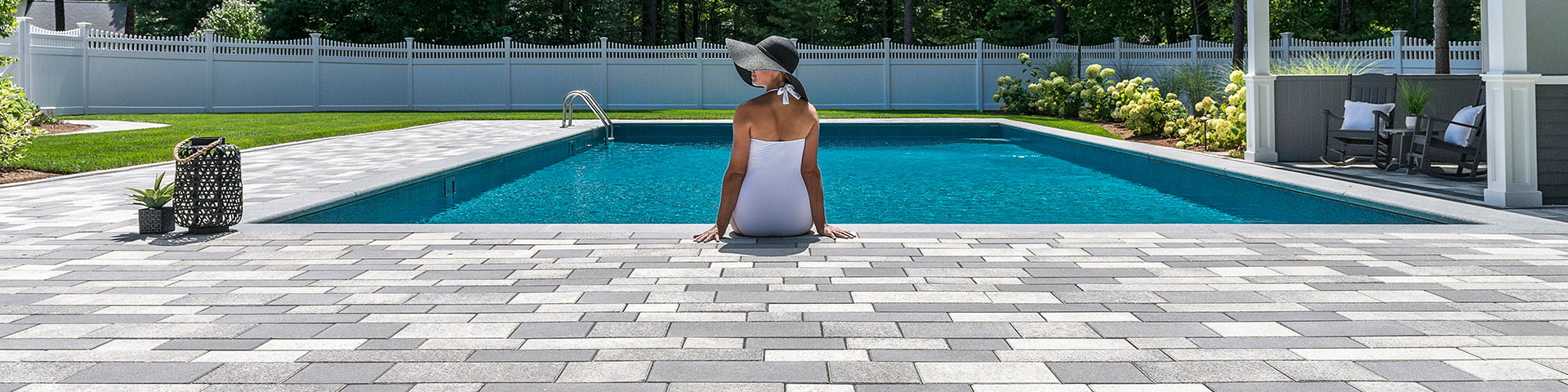 Person Sitting on Unilock Pool Deck with feet in the Pool
