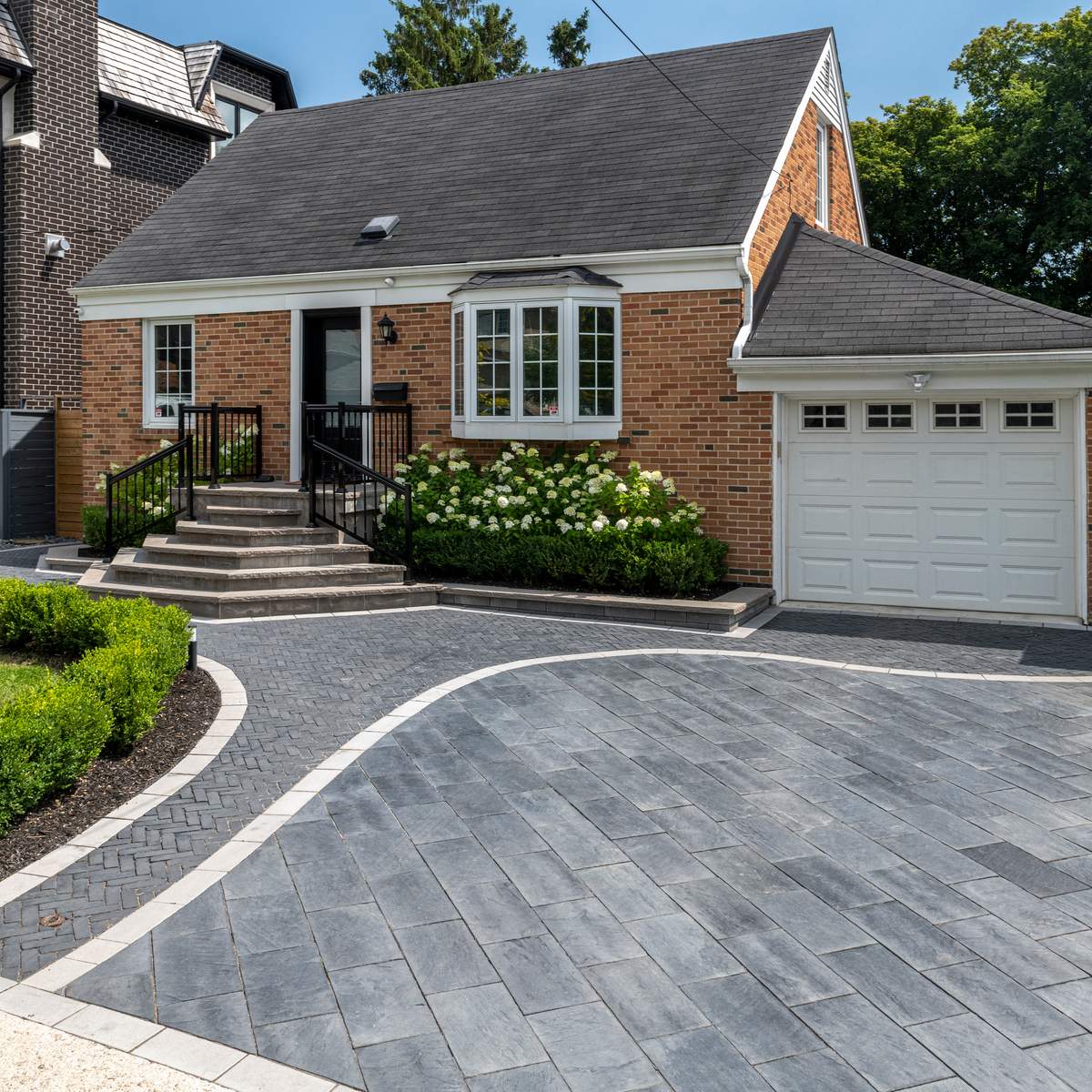 Sweeping interlocking walkway blends with driveway pavers in front of home