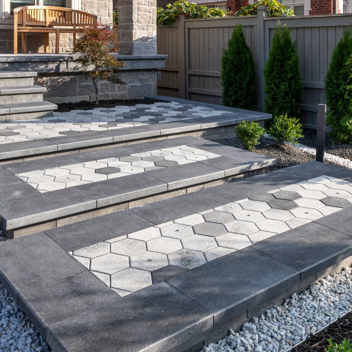 A backyard with a stone walkway and cement paver steps.