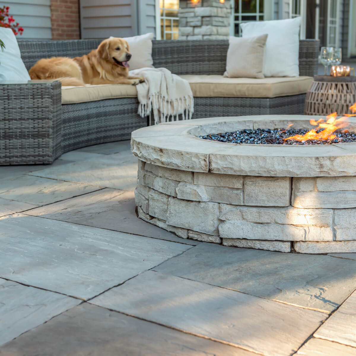 Dog Lounging on Outdoor Patio Couch by Circular Unilock Fire Pit