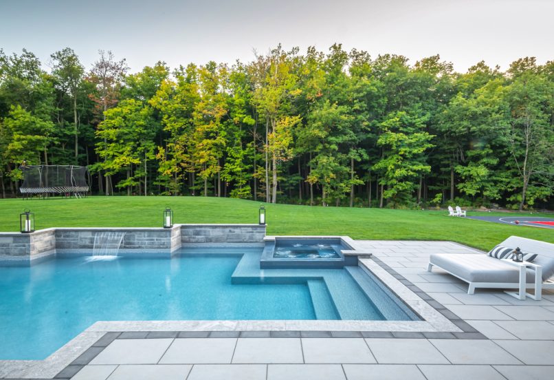 Sleek Pool Deck with Boarders and Waterfall Feature into Pool