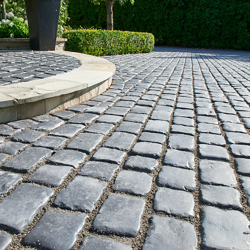 A walkway paved with Unilock landscape pavers in a garden.