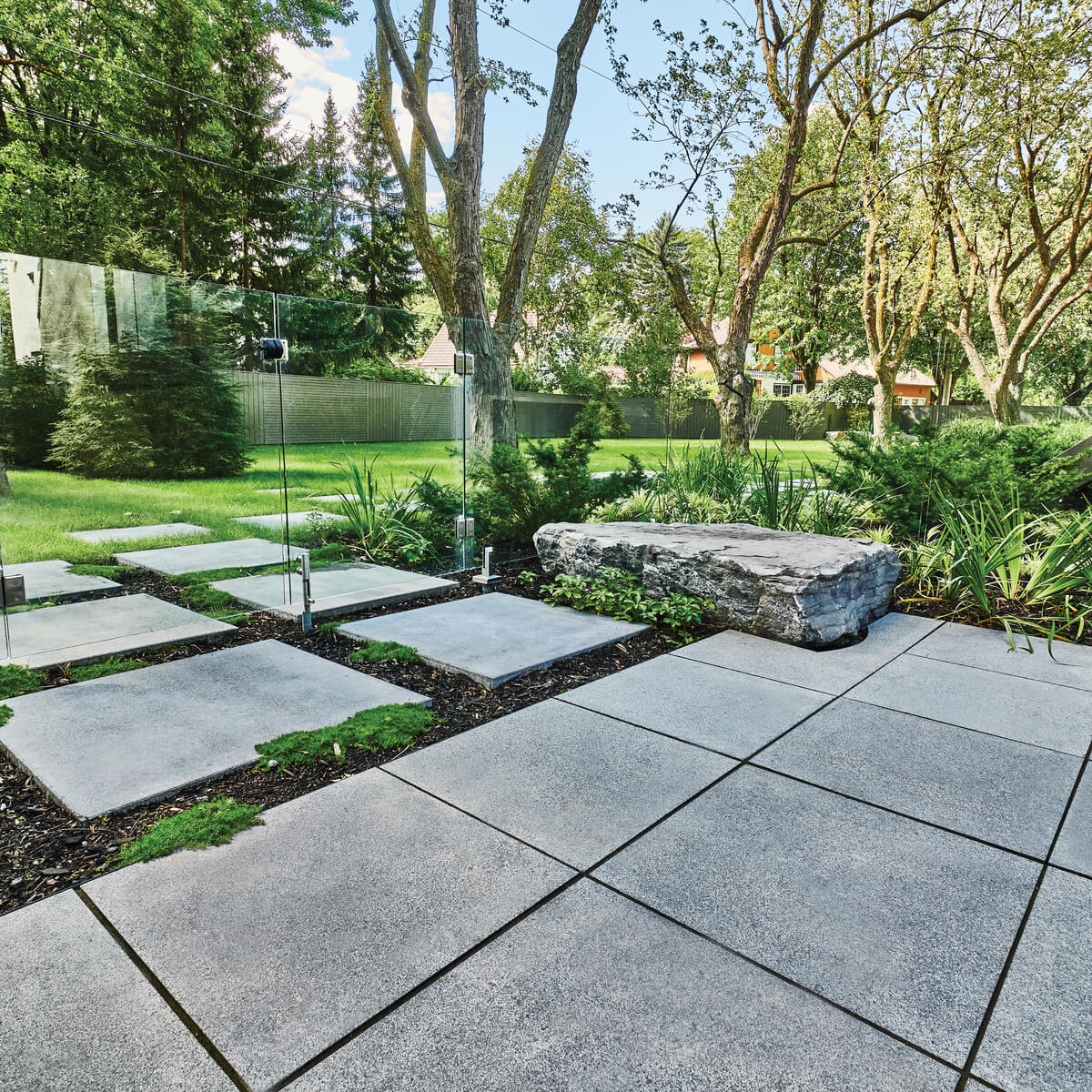 A backyard transformed by Unilock pavers and large square paving slabs