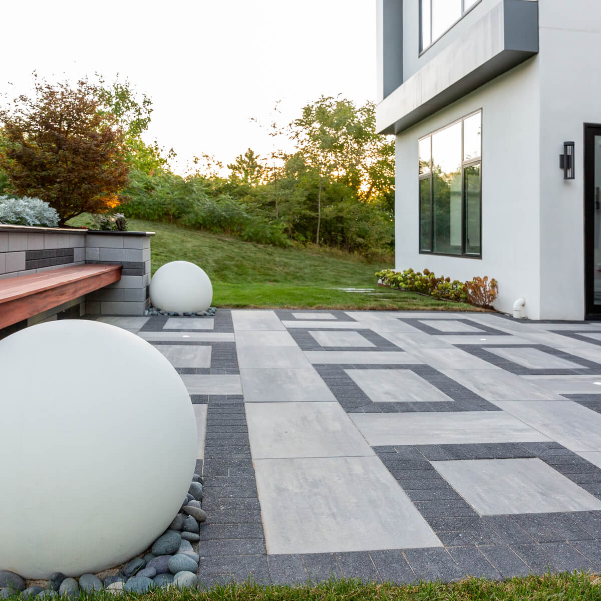 A modern patio with white spheres and Unilock pavers.
