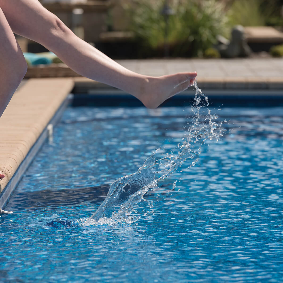 Close up of Person Dipping Foot into Pool with Unilock Coping