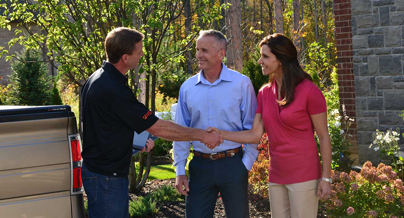 Unilock eco-friendly paver contractor shaking hands with homeowners