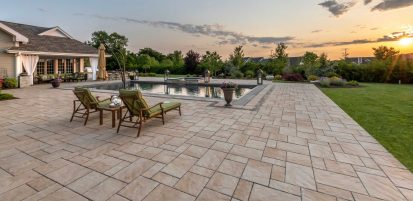 Lounge chairs sitting upon a Unilock Beacon Hill Flagstone paver pool deck with Copthorne accent, with sun setting