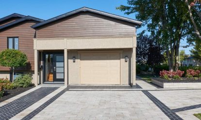 Beige and black Unilock pavers create an intricate pattern leading toward home and garage