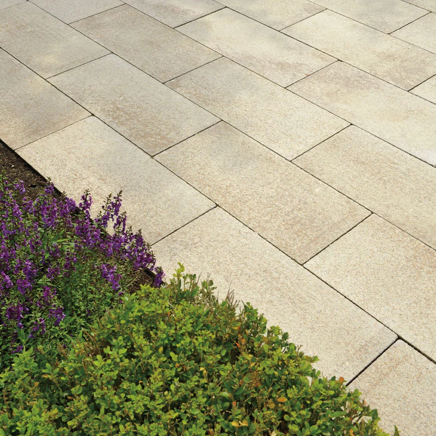 A backyard enhanced with Unilock pavers and surrounded by flowers.