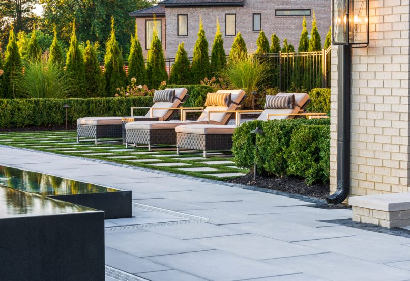 Sleek Unilock Pavers around Raised Pool and Grass Lounge Area with Spaced Pavers