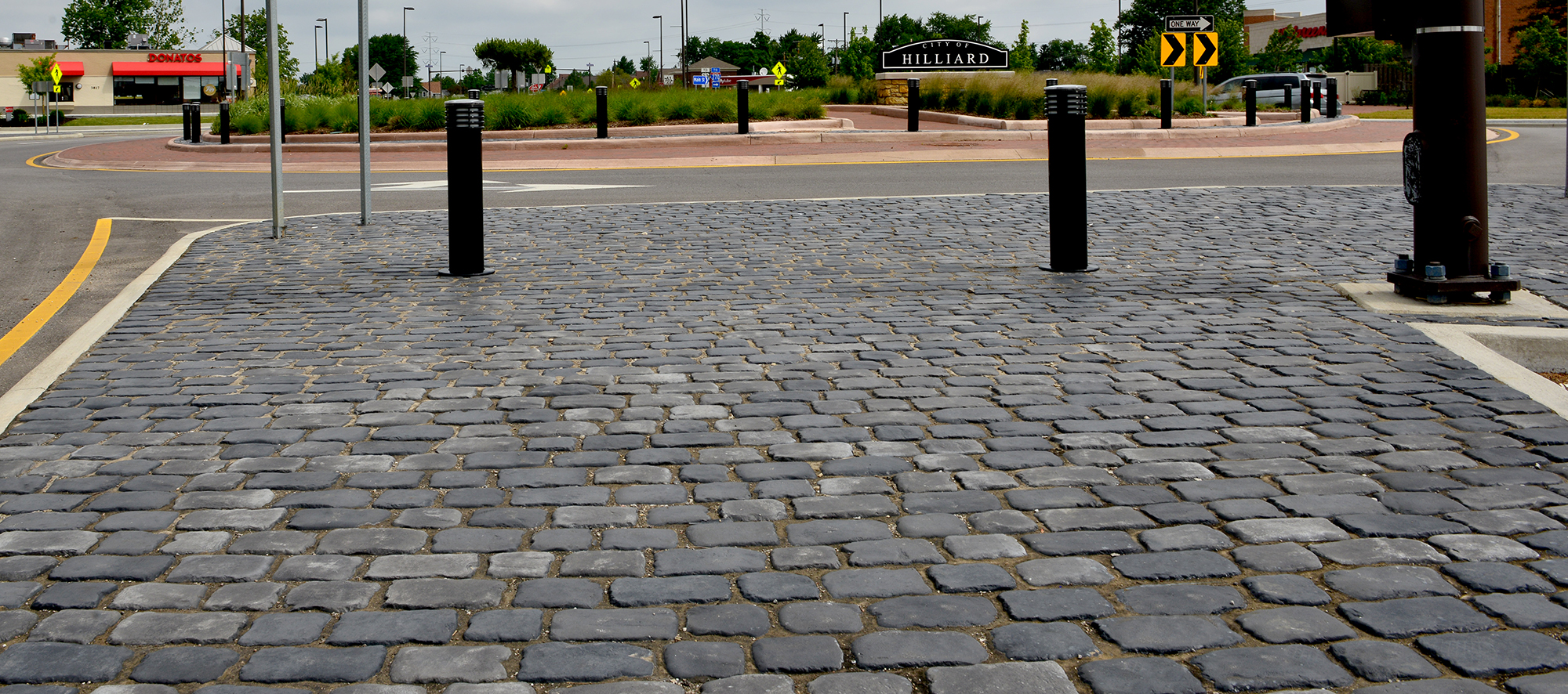 Alongside stores and the City of Hilliard sign at the other end of the roundabout, the walkway is lined with two-toned Courtstone pavers.
