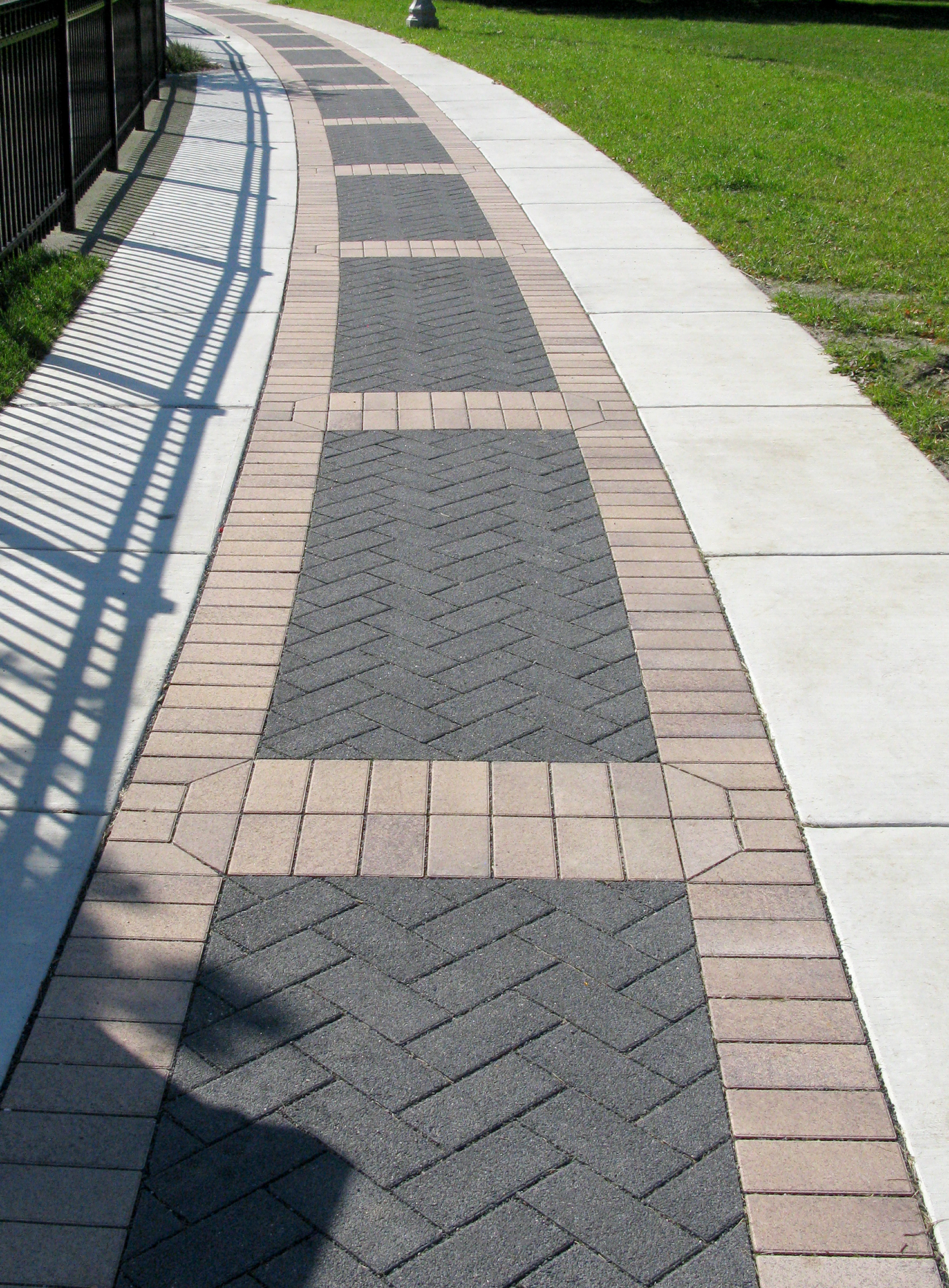 Black Series paver rugs are broken up by thick border bands of Eco-Priora in a warm tone, delineating a walkway along the plaza.