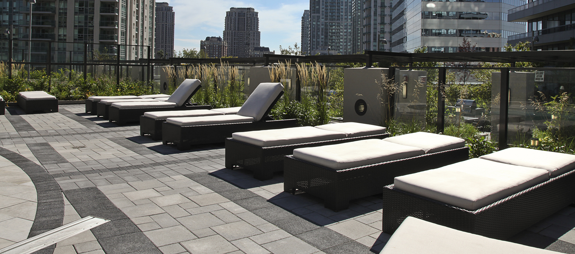 Lounge chairs sit within the borders of black Europaver, intersected by grey Series to create a decorative paver rug on the pool deck.
