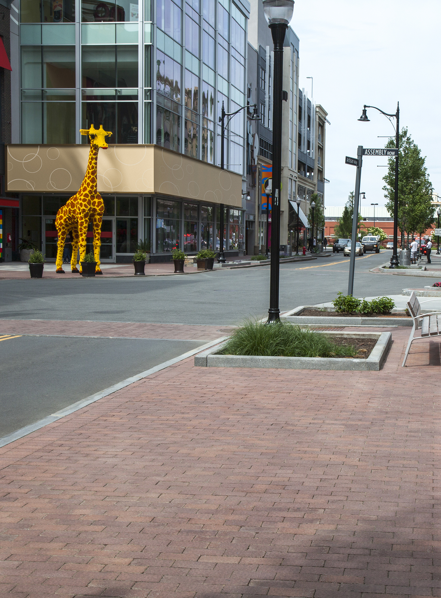 A large giraffe sculpture stands on the corner of Assembly Row with pedestrian areas delineated in Il campo pavers.