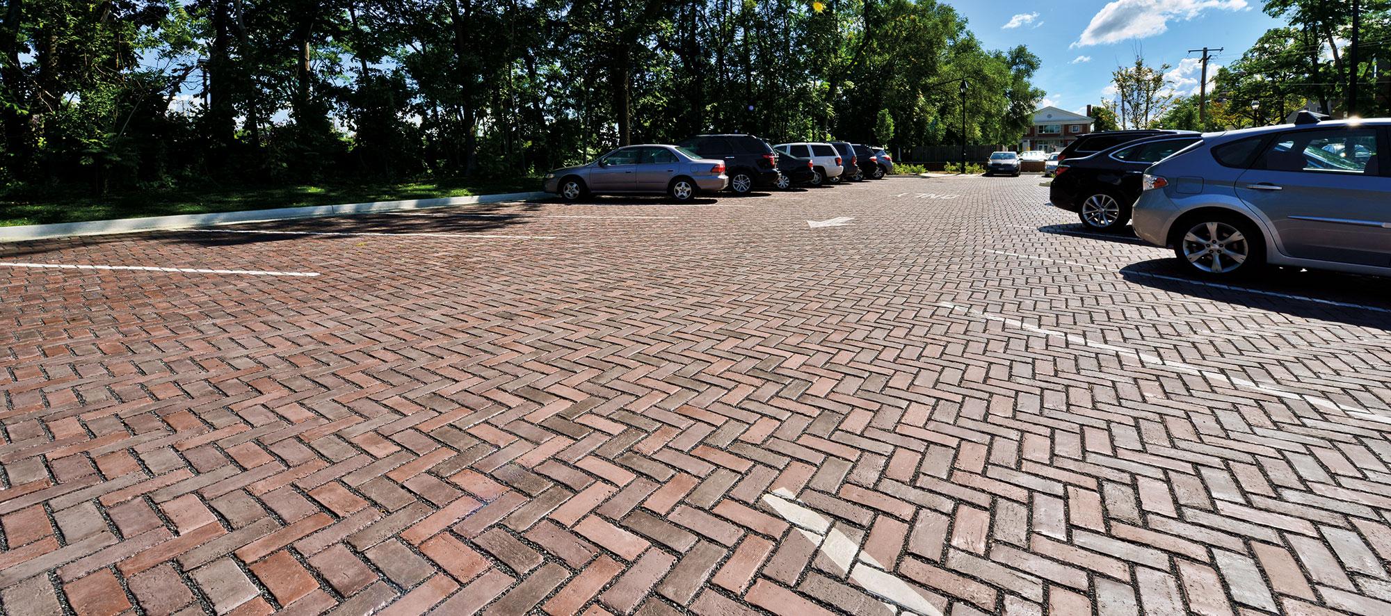 Painted white arrows and parking lines cut through the herringbone pattern of tri-colored Town Hall pavers.