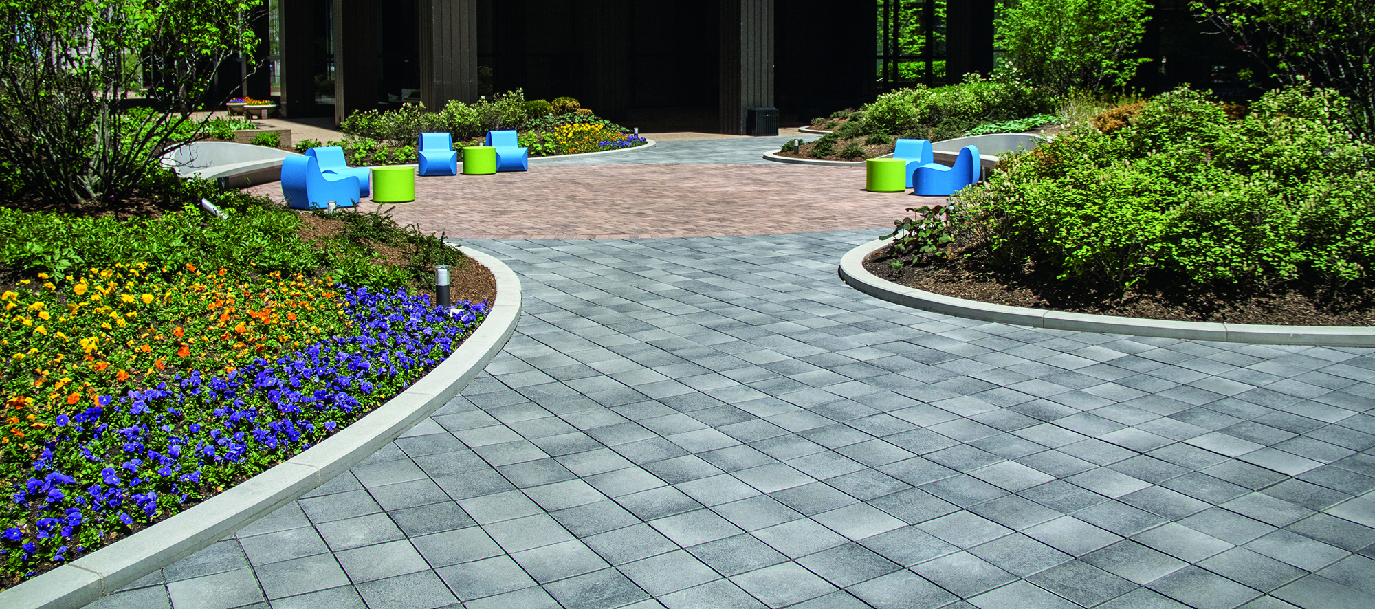 Contrasting colors of Umbriano pavers create a curvy walkway and pedestrian area with green space around it, on a condominium roof deck.