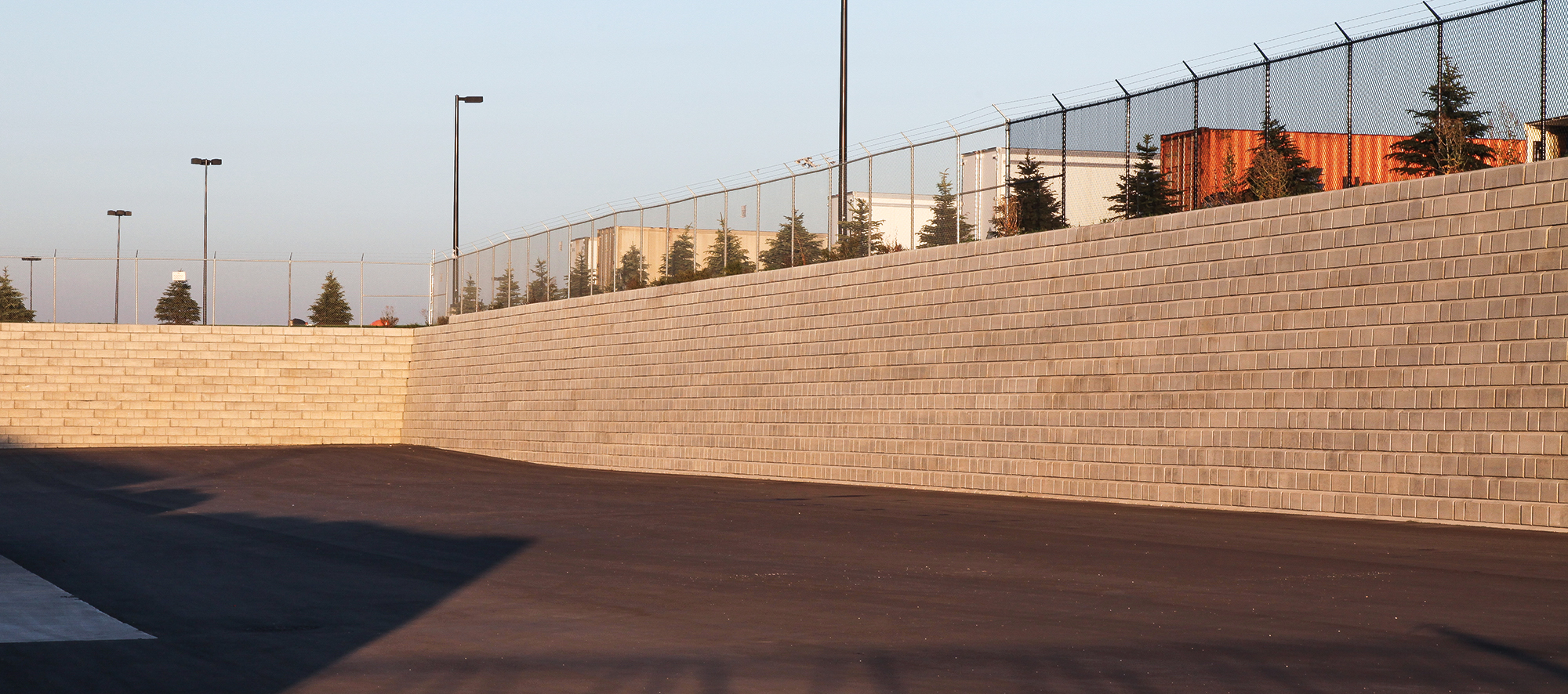 At the Home Depot Warehouse, a sizable DuraHold retaining wall and chain-link fence enclose an open parking area.