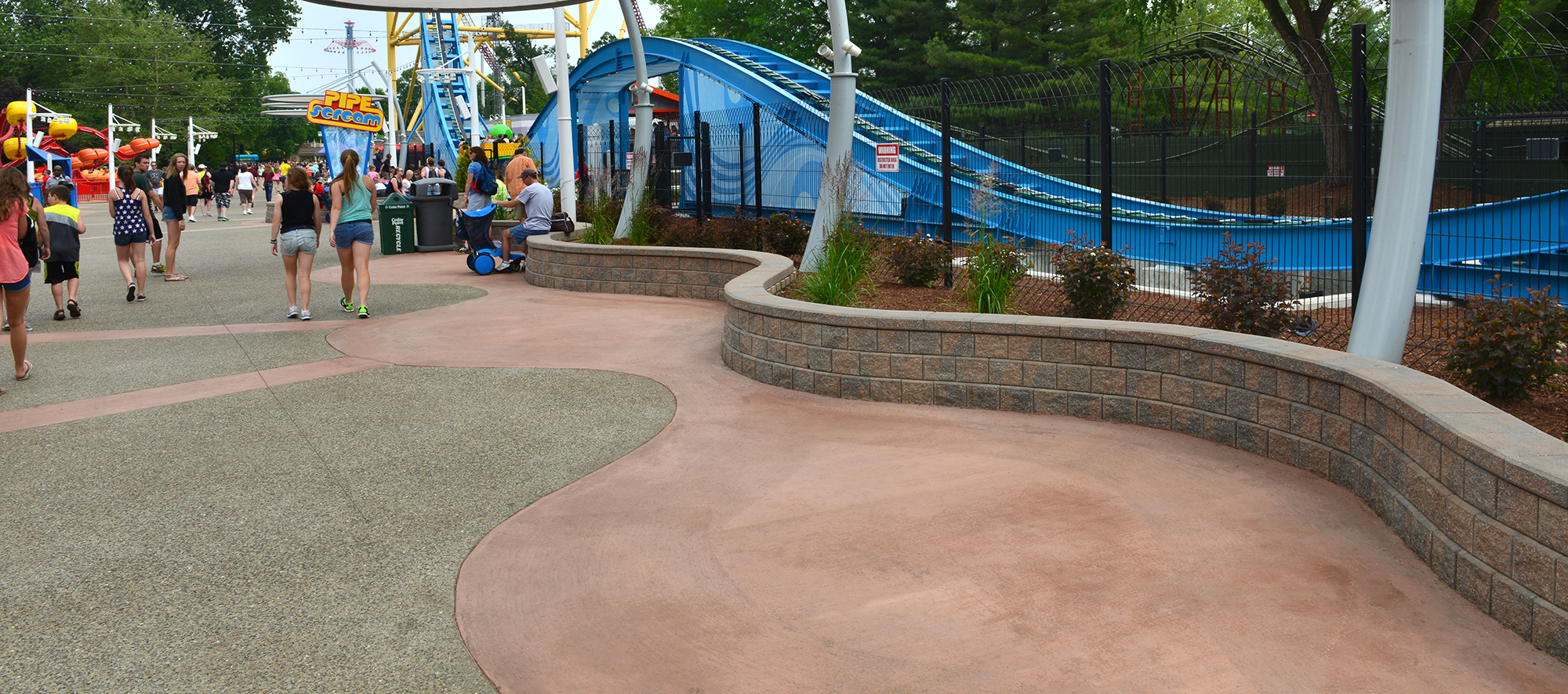 A retaining wall mimics the freeflowing curves of the rollercoaster behind the fence, while providing additional seating for visitors.