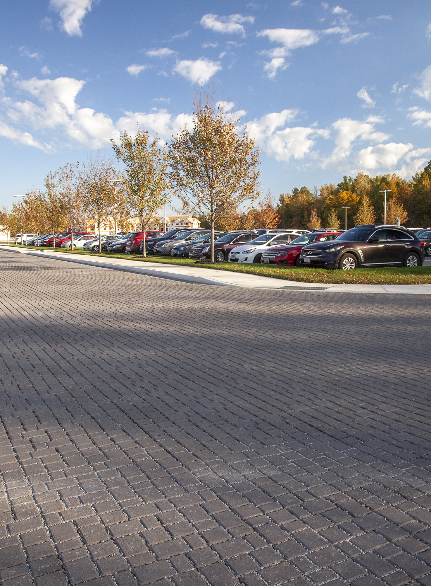 Motor vehicles occupy a busy parking lot at the Cleveland Clinic, featuring a warm dark grey hue of Eco-Optiloc™ pavers throughout the space.