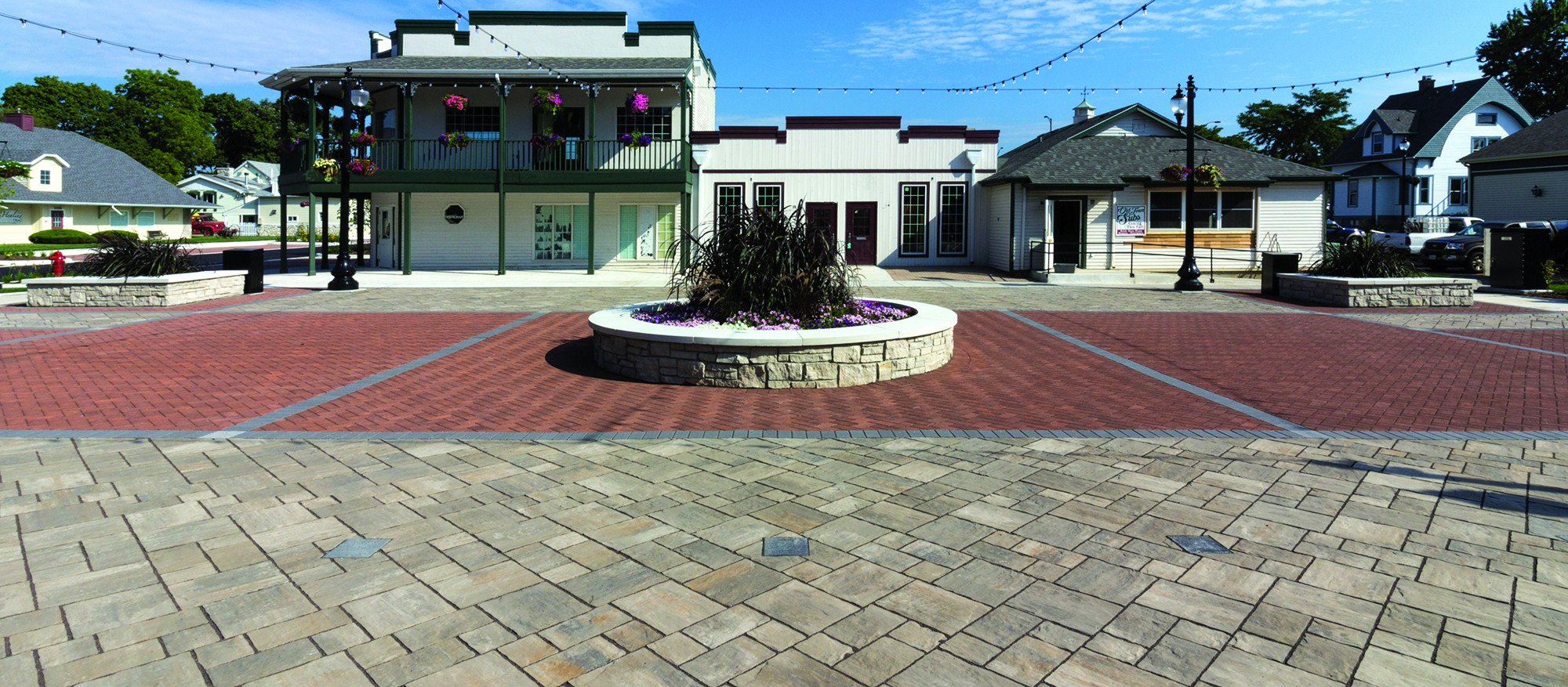 Thornbury and Eco-Priora pavers in geometric shapes and contrasting colors create a pedestrian area with a circular walled garden in the middle.