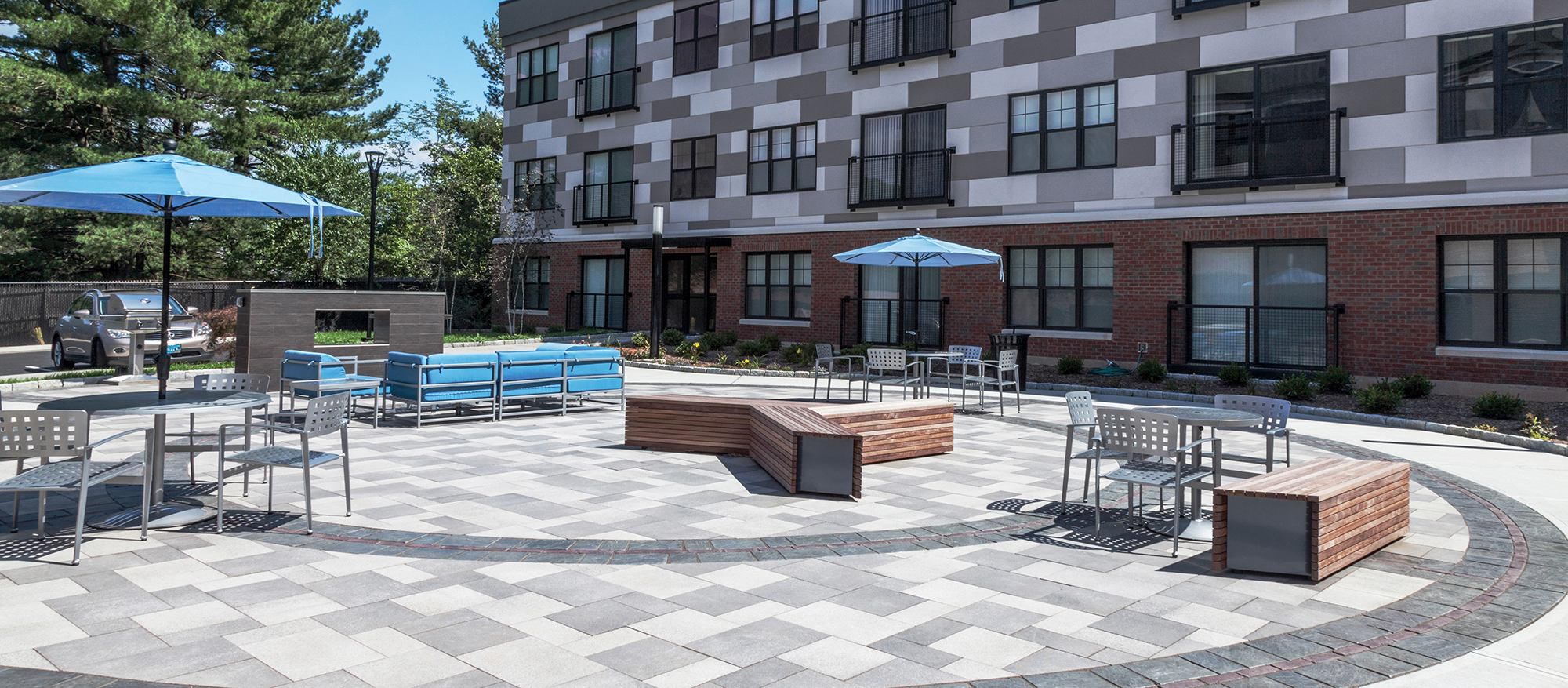 Grey and white Umbriano pavers match the bricks of the apartment building in this outdoor amenity space.