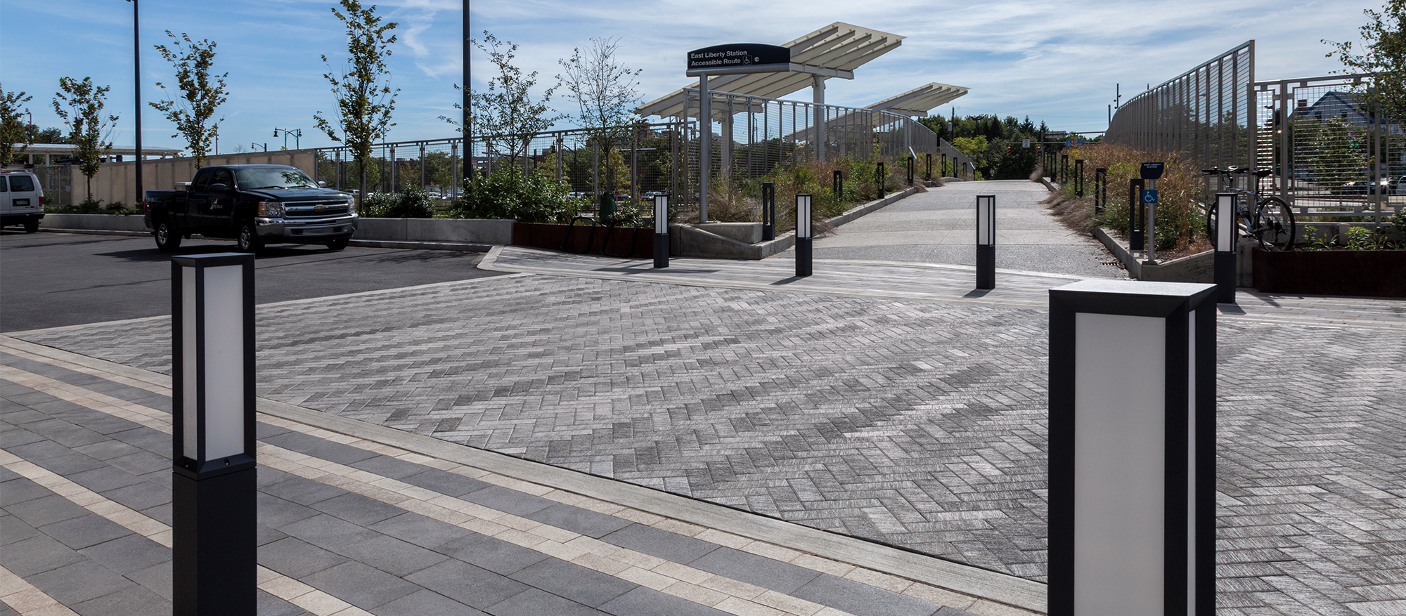 A sidewalk of Il Campo pavers laid in a herringbone pattern in runs through a walkway of Umbriano pavers with dark and light stripes.