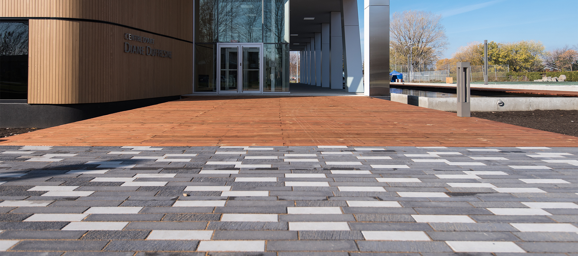 Tri-colored Il Campo pavers transition to a boardwalk-style walkway at the front entrance of the building.