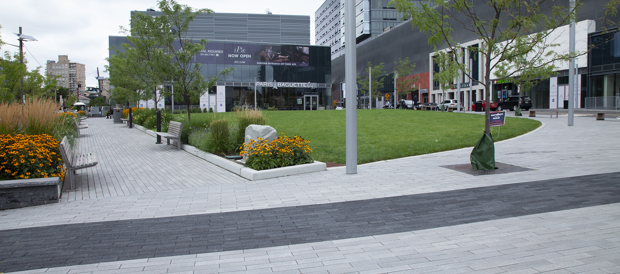 Grey and black Promenade Planks laid in a running bond pattern lead to the entrance, passing a set of garden islands and park benches.