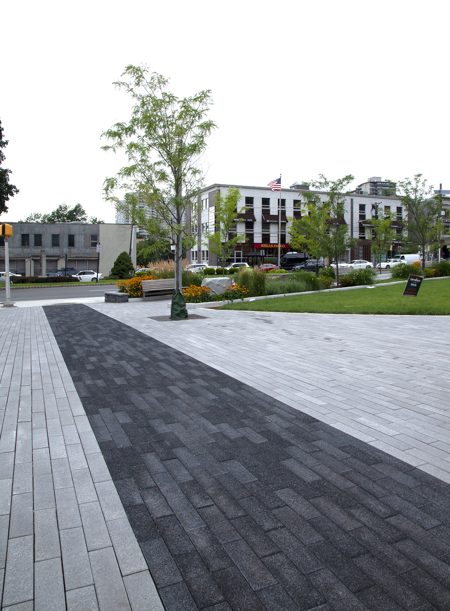 Moving in a running bond pattern, black Promenade Planks lead straight toward the roadway slicing through a sea of grey pavers.