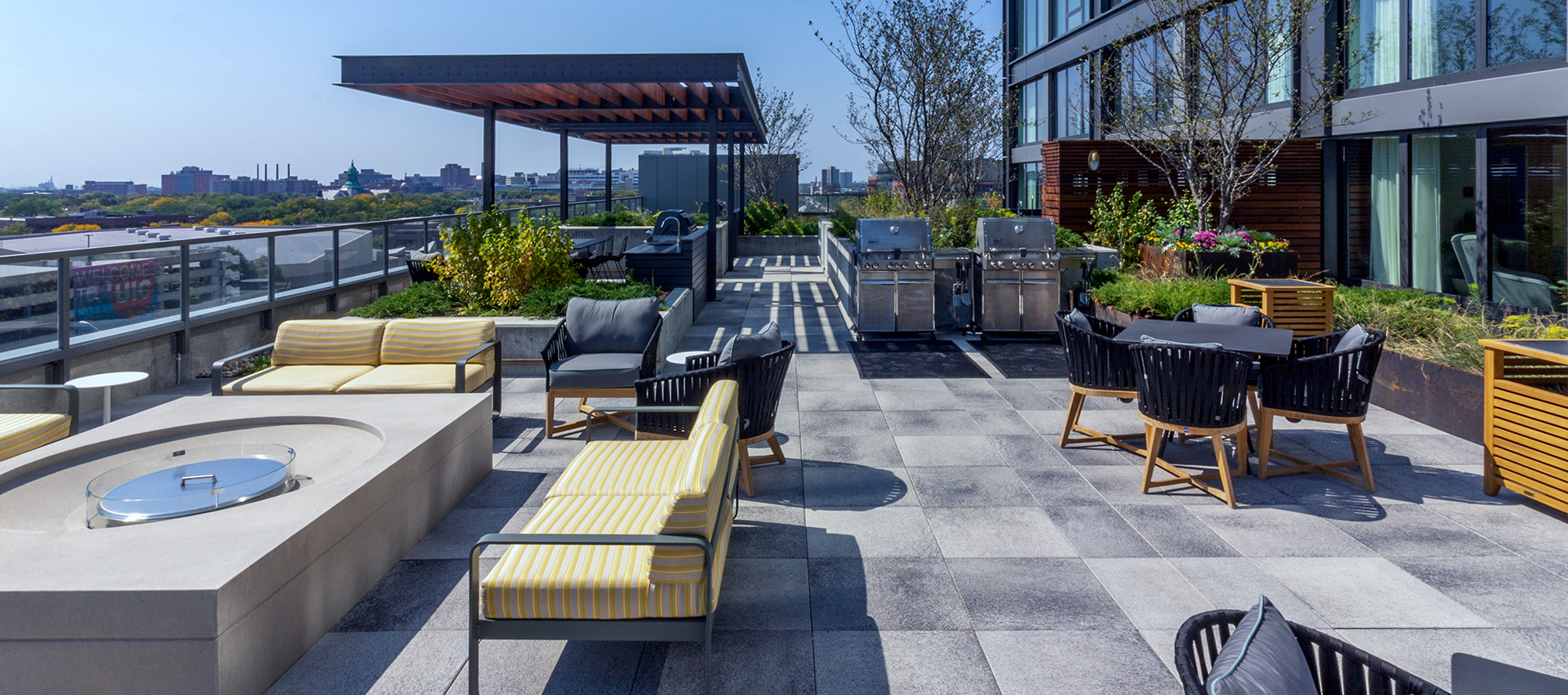 A roof deck overlooking the Chicago skyline features grey speckled Umbriano slabs and outdoor amenities including an outdoor kitchen.