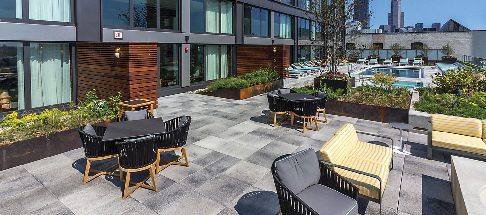 A roof deck overlooking the Chicago skyline features grey speckled Umbriano slabs and outdoor amenities including a pool and lounge area.