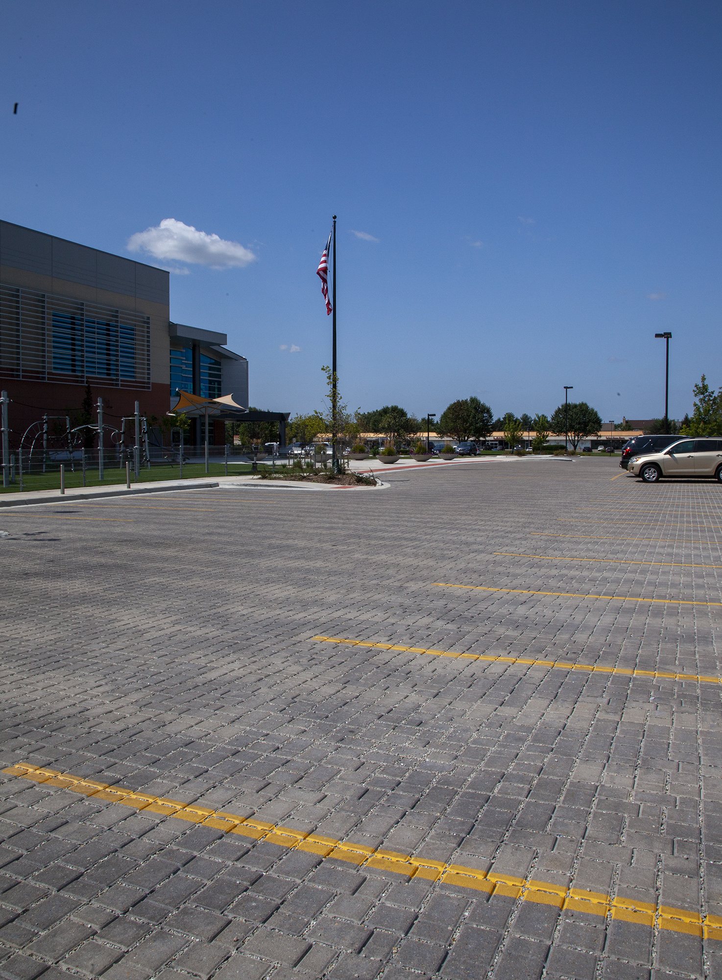 Cars park in between yellow lines on Eco-Optiloc permeable pavers in front of the Athletic and Recreation Center in Woodridge Illinois.