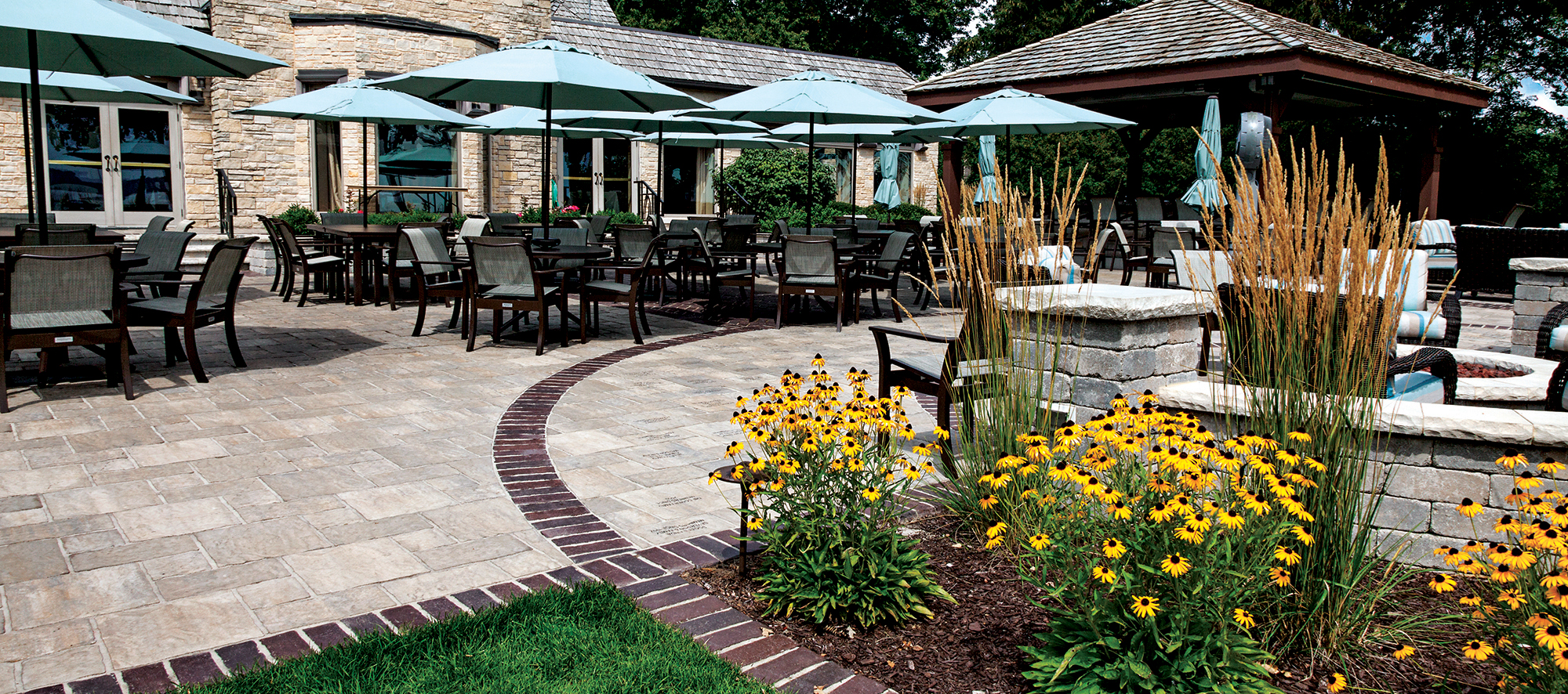 This entrance has patio furniture on Thornbury pavers with lines of contrasting pavers extending to a garden in front of an Old Quarry wall.
