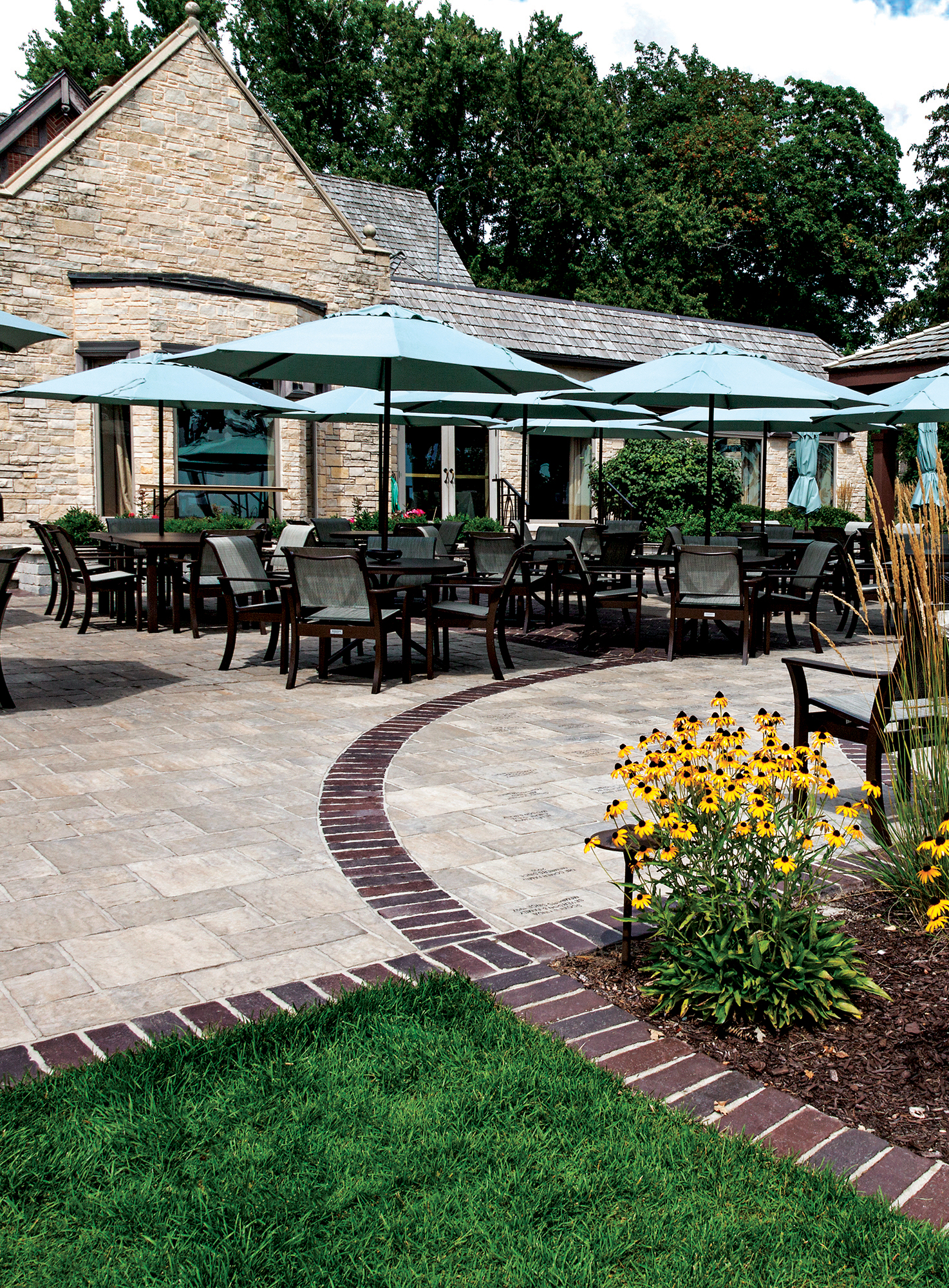 This entrance has patio furniture on Thornbury pavers with lines of contrasting pavers extending to a garden in front of an Old Quarry wall.