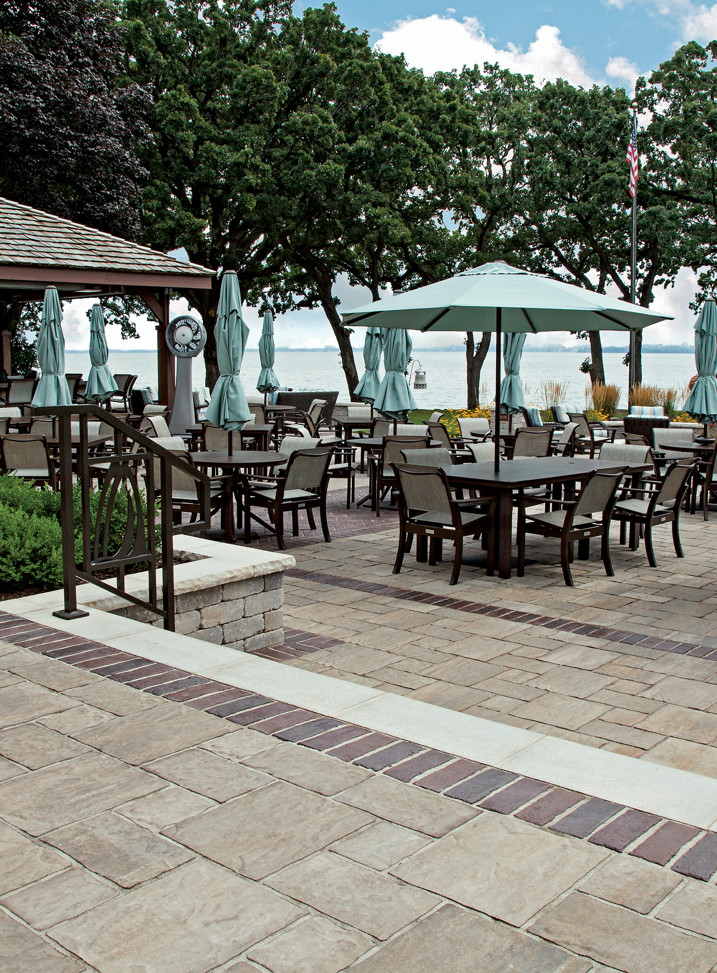 Overlooking the water, chairs and tables with umbrellas and a pavilion sit on Thornbury pavers with accents of Town Hall pavers.