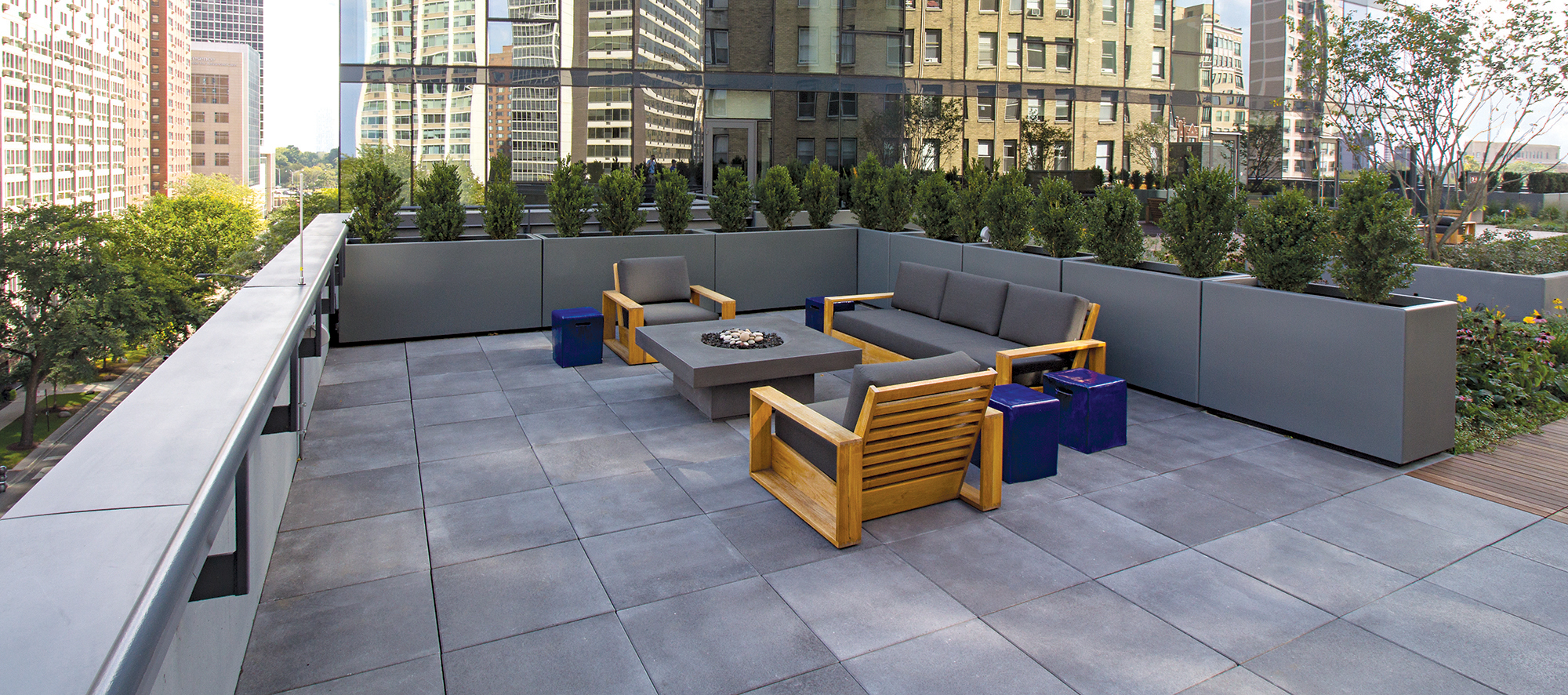 A roof deck on a glass building reflecting the Chicago skyline is paved with Unilock Umbriano slabs in Midnight Sky.