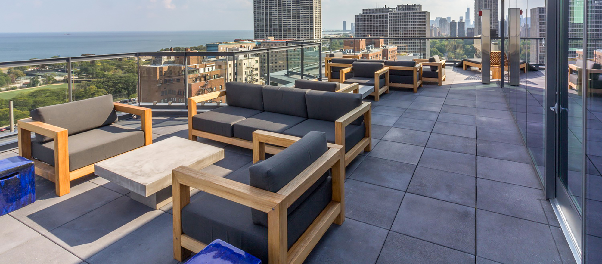 Unilock Umbriano Slabs lay the groundwork for a condominium roof deck with modern patio furniture and a view of the Chicago skyline.