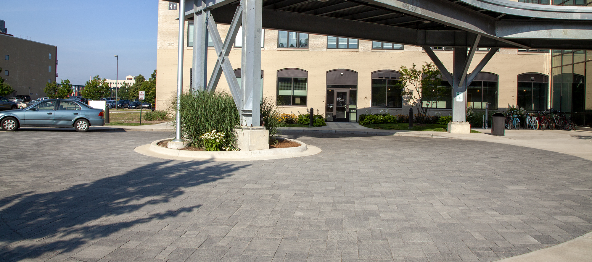 In front of 616 Lofts on Monroe is a circular driveway made from Unilock Il Campo pavers in shades of grey, with landscaping and amenities.