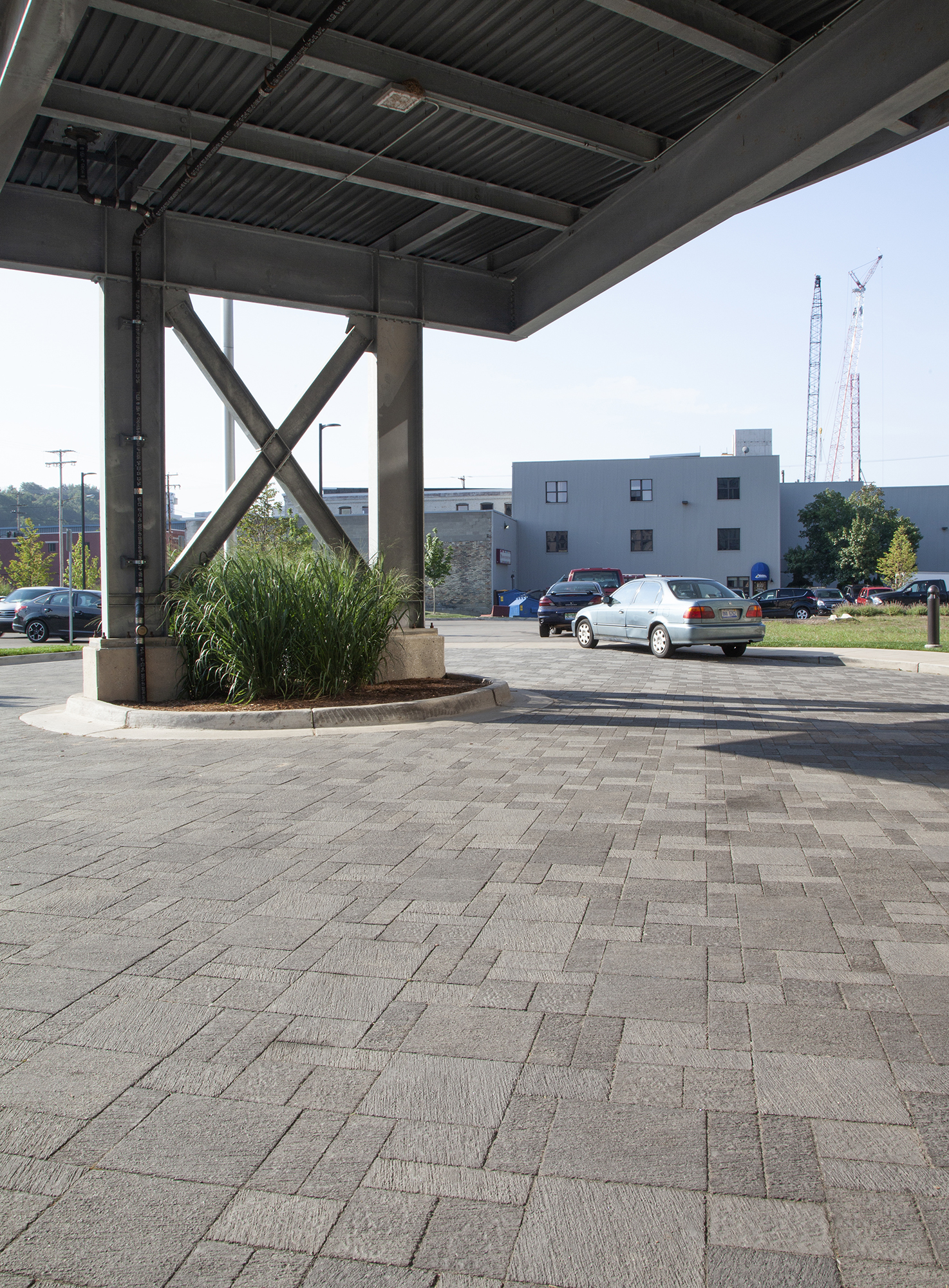 A large circular driveway with Unilock Il Campo pavers in different shapes and shades of grey under a loading shelter.