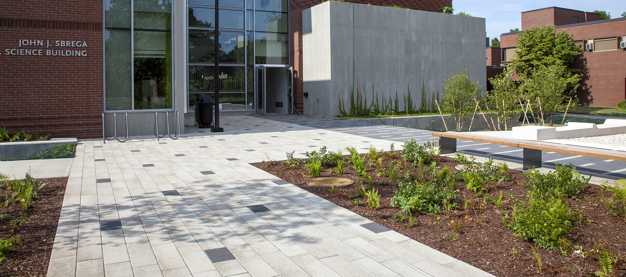The entry of the John J.Sbrega Science Building has bike racks, gardens and lights, with patterned paths paved in Promenade Plank.