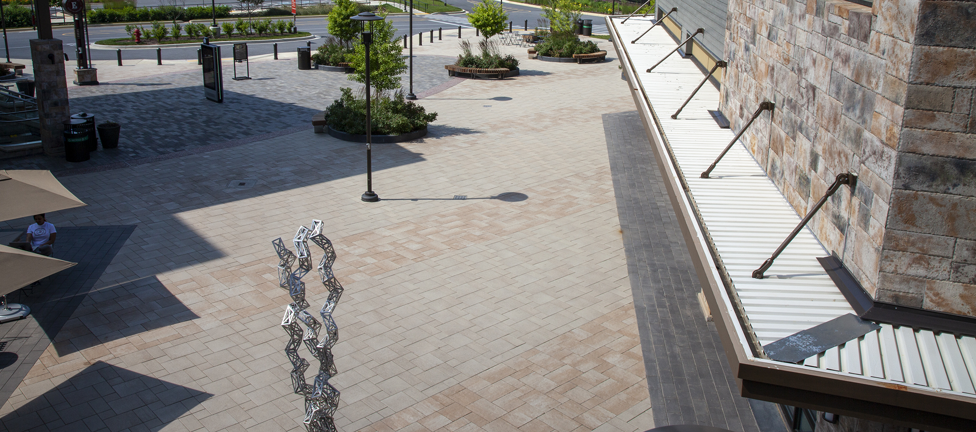 Bristol Valley in beige and tan hues are laid on a 45 degree angle, leading toward storefronts in this expansive outdoor plaza.