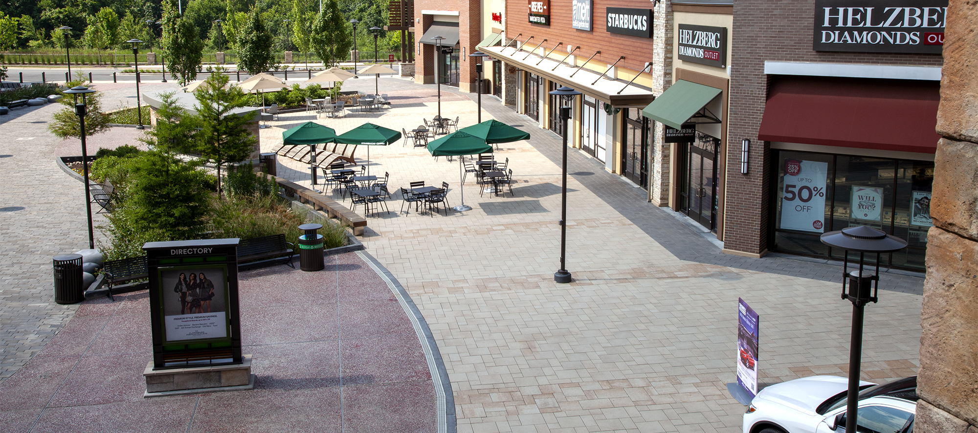 A circular medallion feature captures the reflection of grey Artline pavers, with park benches, tables and chairs.
