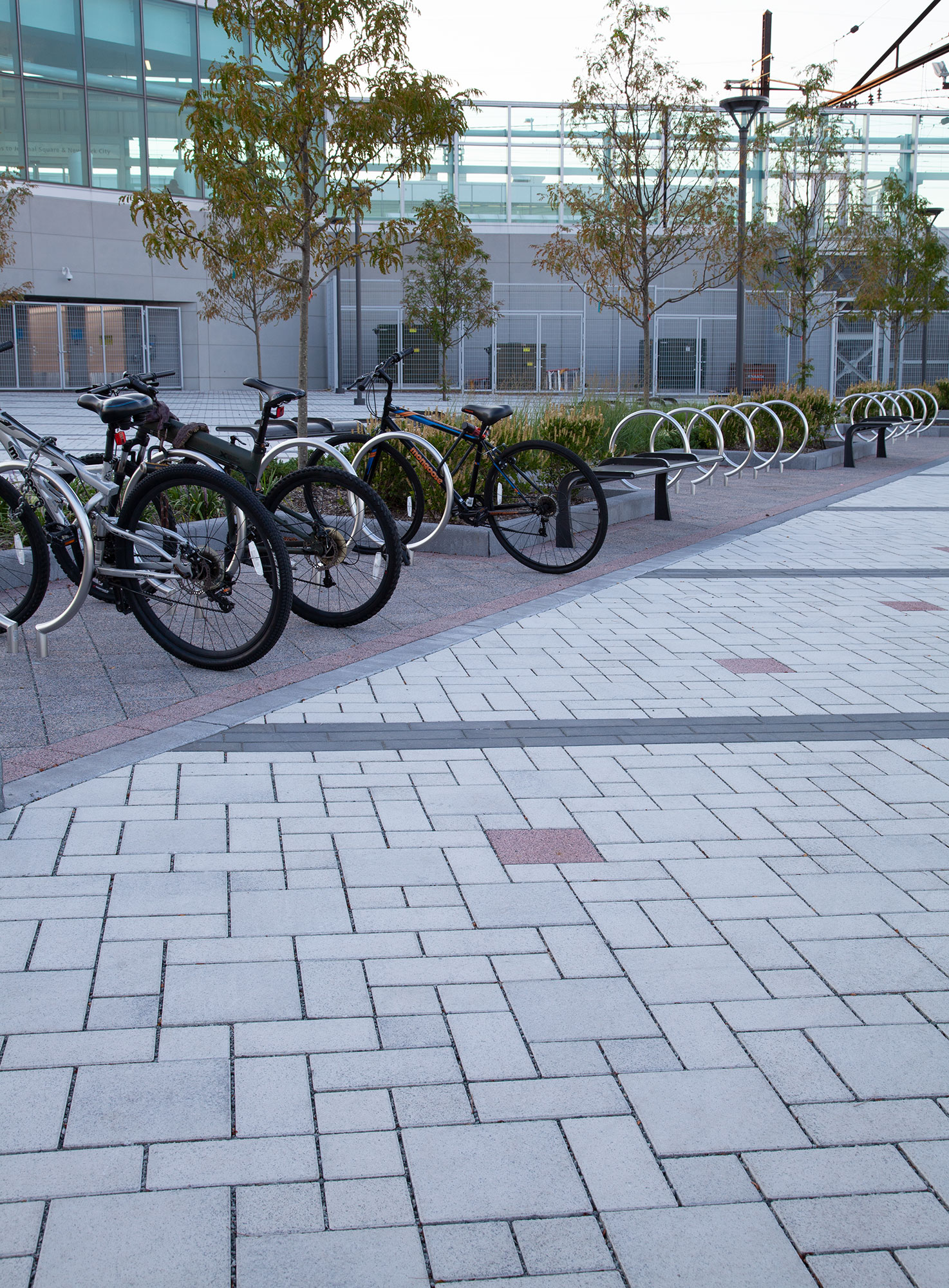 Bikes are parked on black Eco-Priora pavers, near a geometrically patterned paver floor made of white Eco-Priora and black Eco-Promenade.