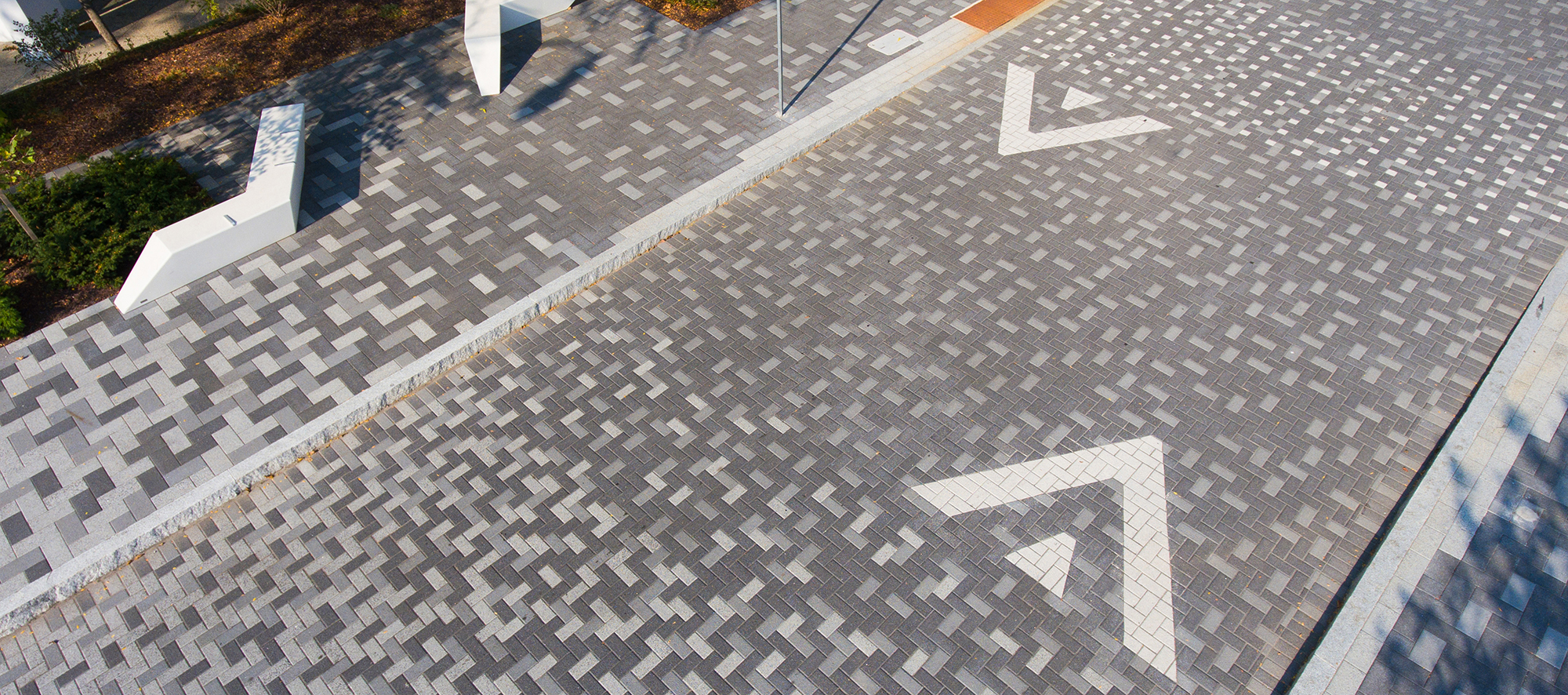 A vibrant, pixelated design using Series pavers features directional arrows for vehicular traffic, and elevated walkways for pedestrians.